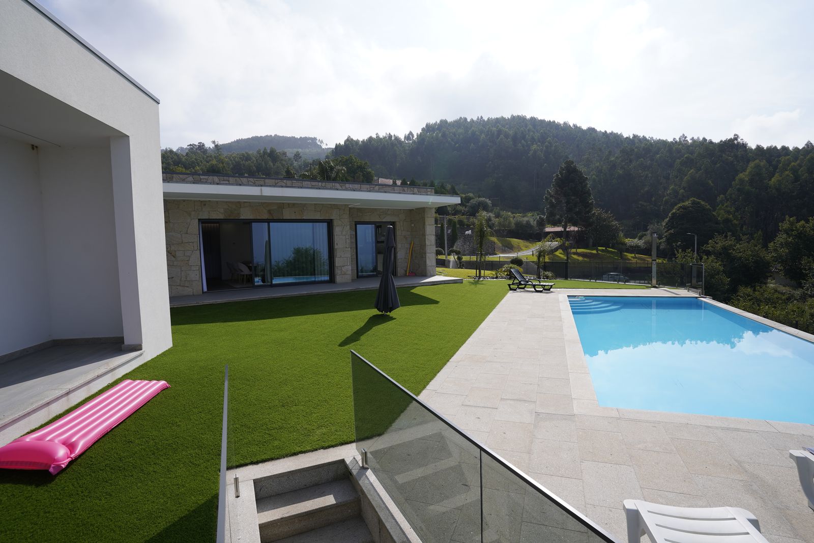 Jardim relvado e ala em pedra com grandes envidraçados